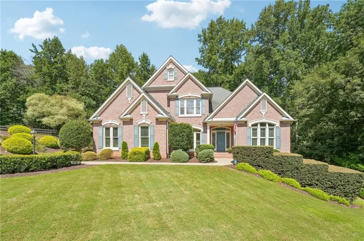 Brick exterior with multiple gables, arched entry, and shuttered windows