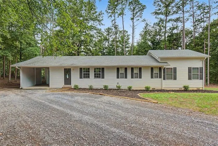 Ranch-style residence featuring white siding, a gray shingle roof, and black window shutters