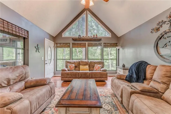 Living area featuring high vaulted ceiling, light wood-type flooring, plenty of natural light, and ceiling fan