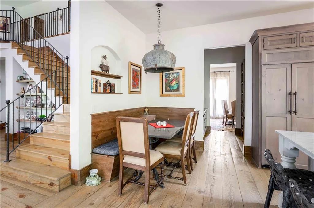 Built-in dining nook with wood-finish flooring, recessed wall shelving, and a decorative pendant light
