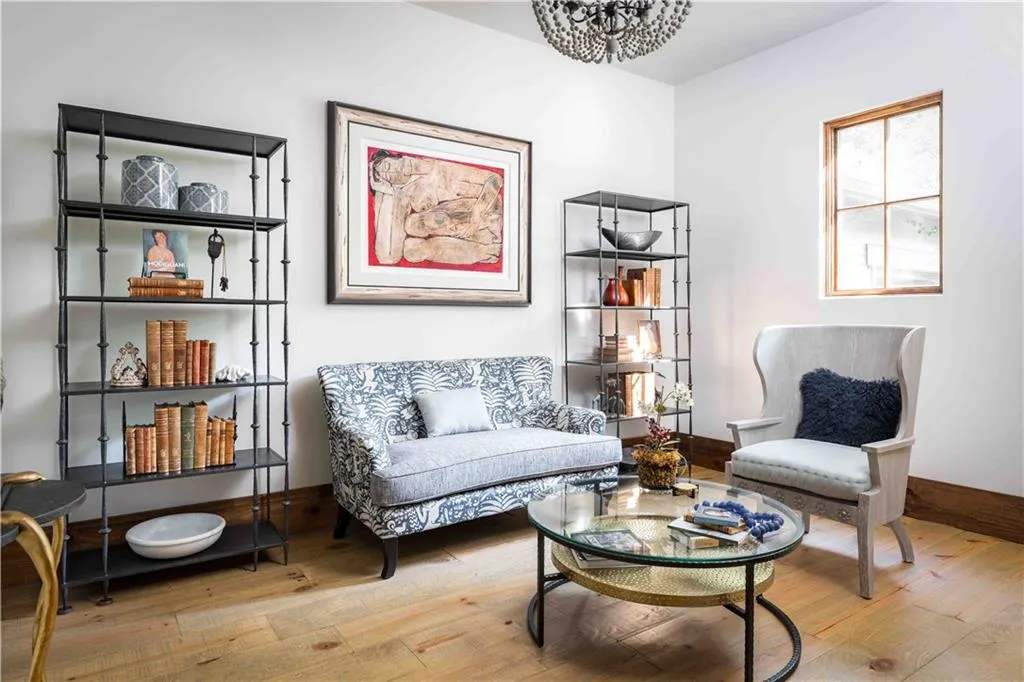 Light wood-finish flooring complements white walls in this space featuring a multi-pane window with wood trim