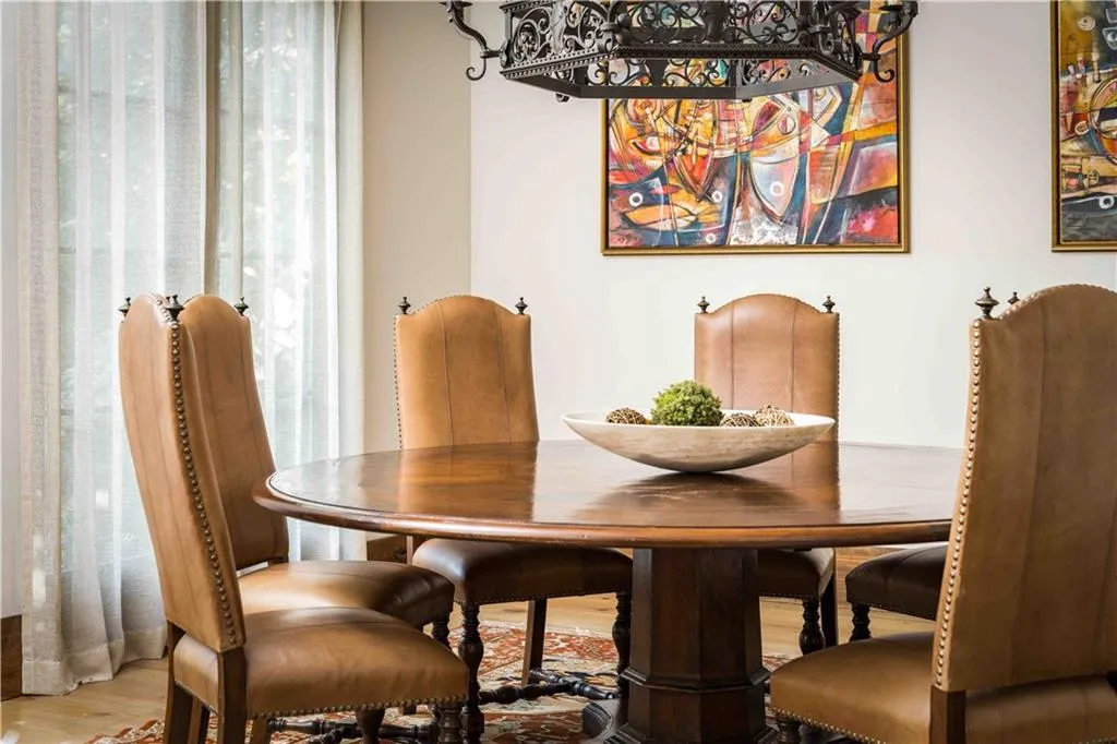 Spacious dining area featuring a round pedestal dining table, leather-upholstered chairs with nailhead trim, and hardwood flooring