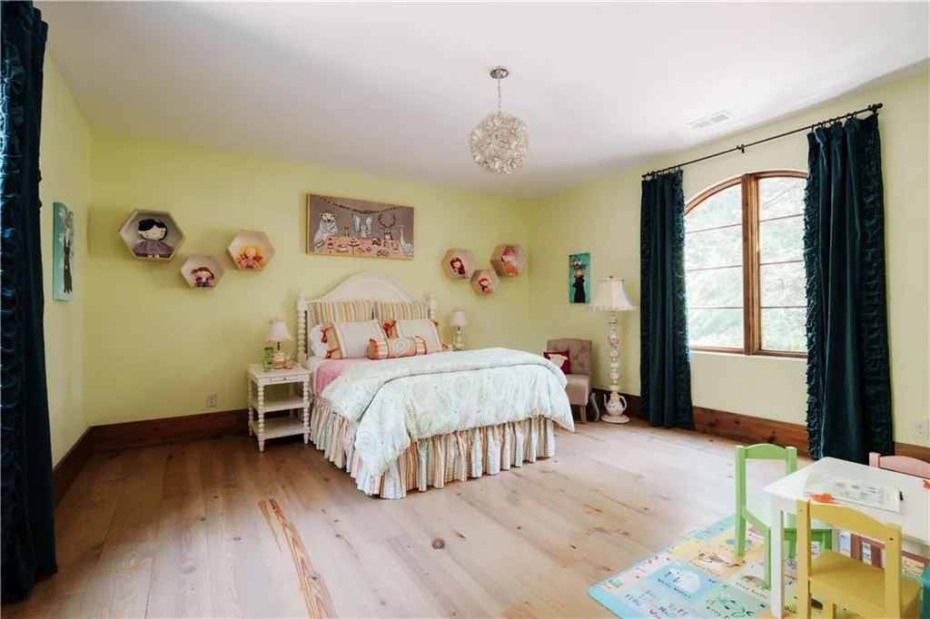 Spacious bedroom with wood-finish flooring, a large arched window, and recessed lighting