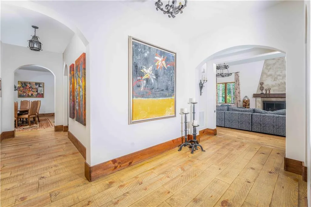 Wide plank wood-finish flooring extending throughout, complemented by arched doorways