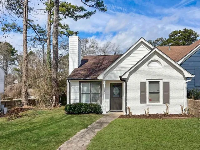 Bungalow featuring a front lawn, a chimney, brick siding, and a shingled roof