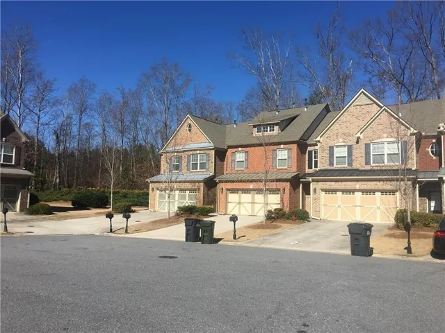Brick and siding townhome featuring a two-car garage, pitched roofline, and dormer windows