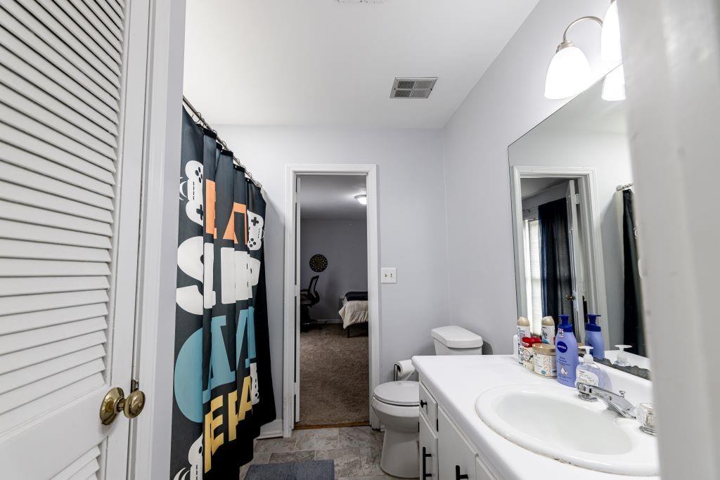 Bathroom featuring toilet, vanity with extensive cabinet space, and tile floors