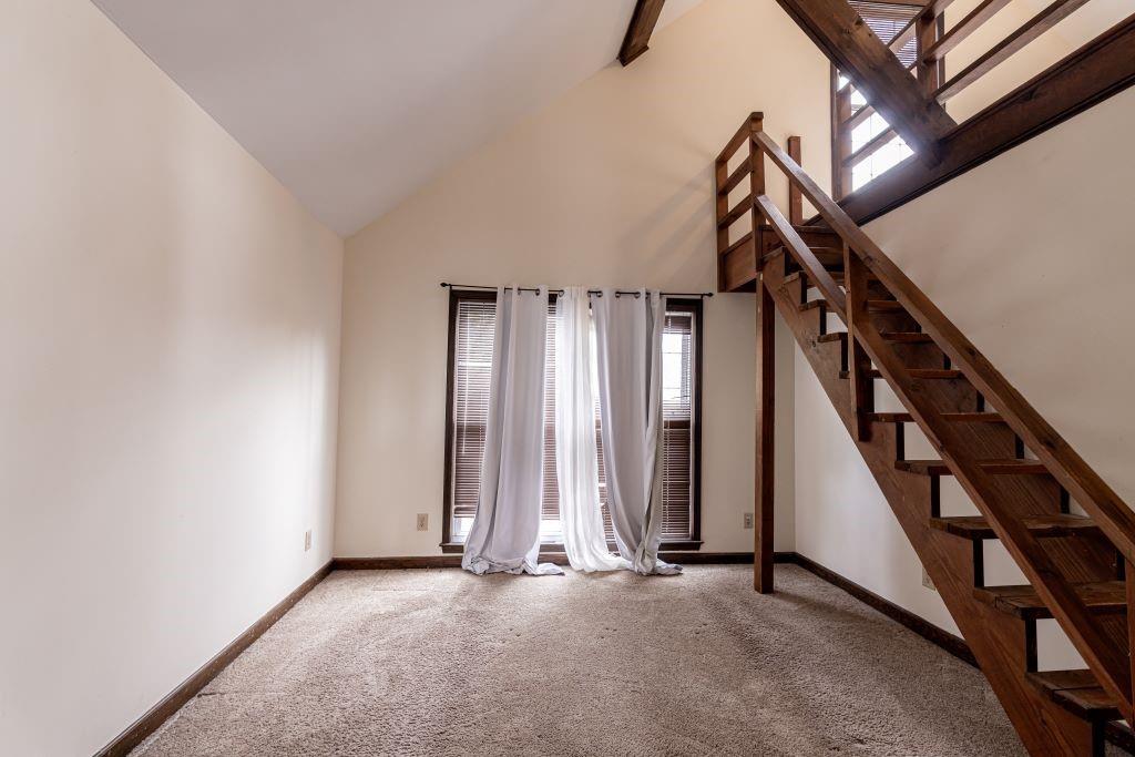 Stairs with a healthy amount of sunlight, carpet floors, and high vaulted ceiling