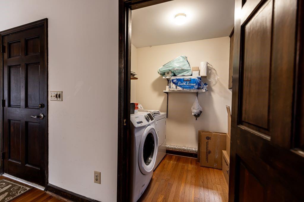 Laundry room with washer and clothes dryer and dark hardwood / wood-style floors