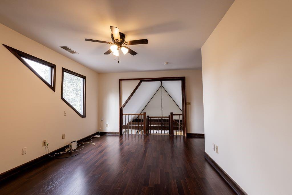 Unfurnished room with ceiling fan and dark wood-type flooring