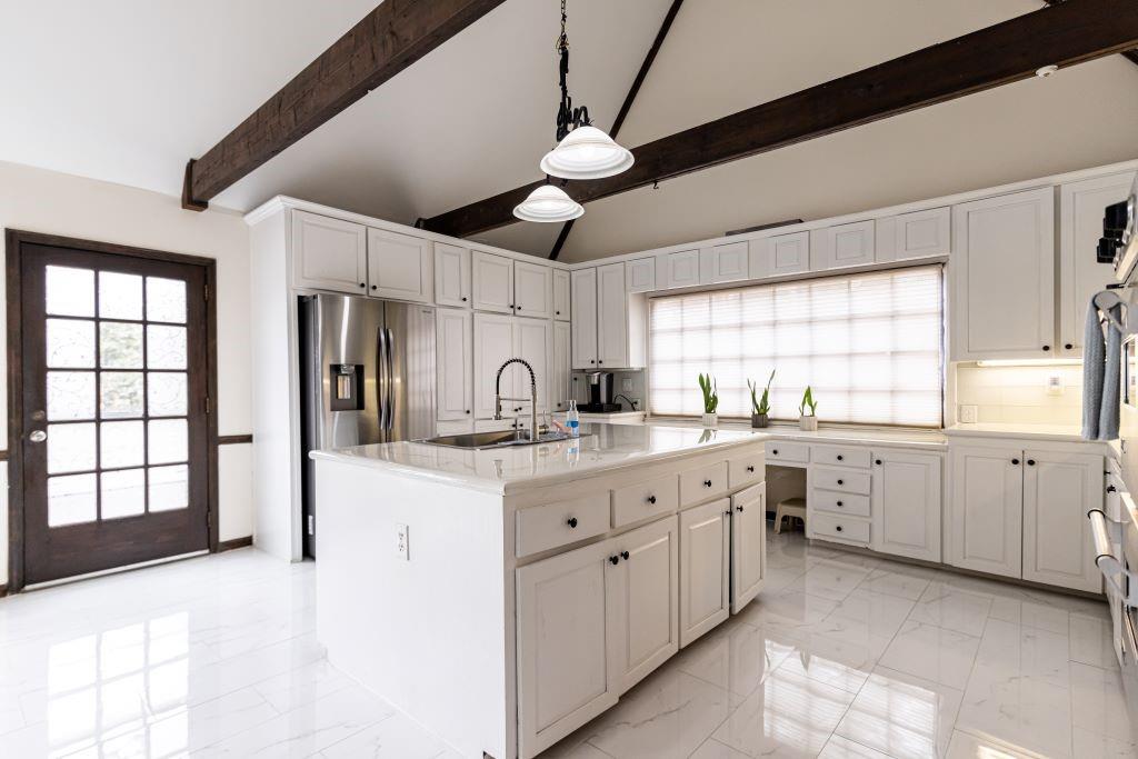 Kitchen with a kitchen island with sink, light tile floors, pendant lighting, and plenty of natural light