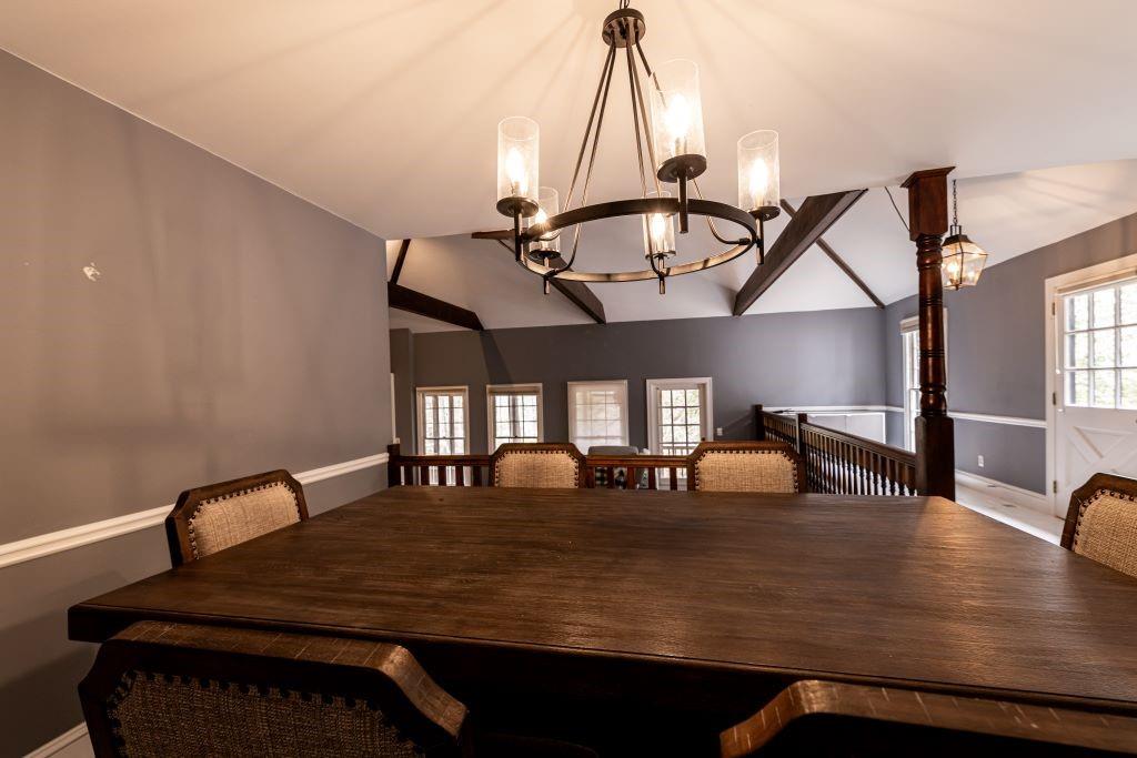 Dining space with hardwood / wood-style flooring, vaulted ceiling, and a notable chandelier