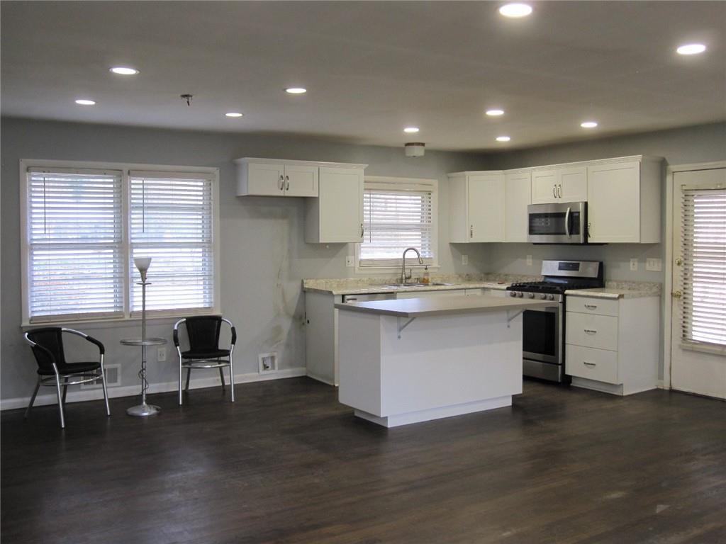 Open light & bright plan with  amount of sunlight, dark hardwood flooring, white cabinetry, and appliances with stainless steel finish es