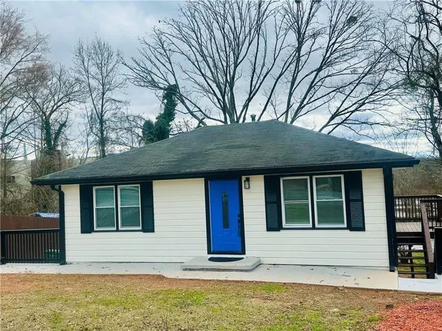 Charming ranch home featuring a crisp white exterior with dark green shutters and a striking blue entry door