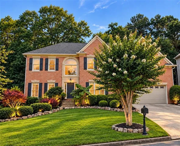 Brick exterior with arched window, dark shutters, and a two-car garage