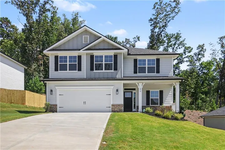 Two-story residence featuring light gray siding with dark shutters, a two-car garage, and a covered entry with stone accents