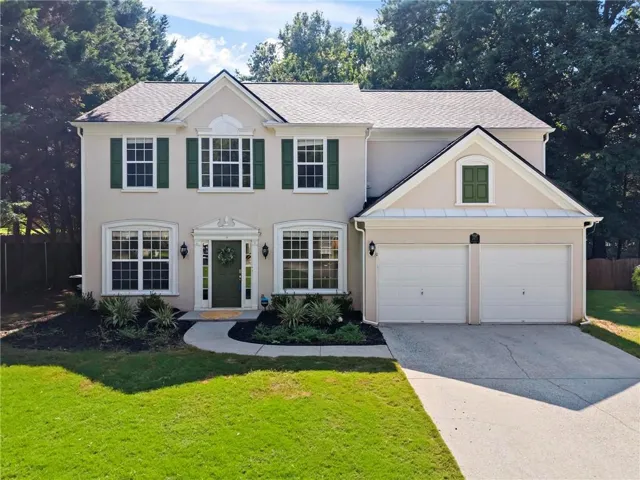 Exterior featuring a two-car garage, manicured lawn, and a paved driveway