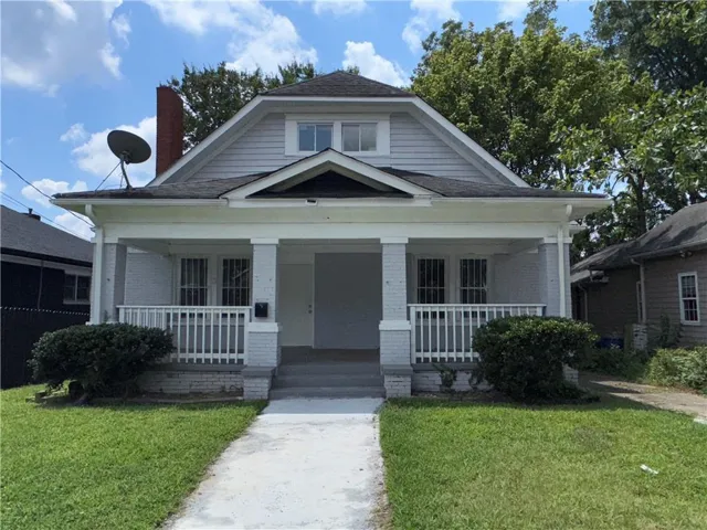 Bungalow-style house featuring a front lawn, covered porch, and brick siding