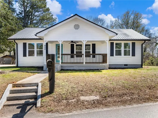 View of front of property featuring a porch, a front yard, crawl space, and a metal roof