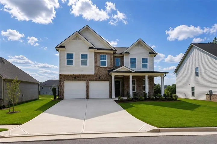 Two-story residence featuring a brick and siding exterior, a covered front porch with white columns, a two-car garage, and a concrete driveway