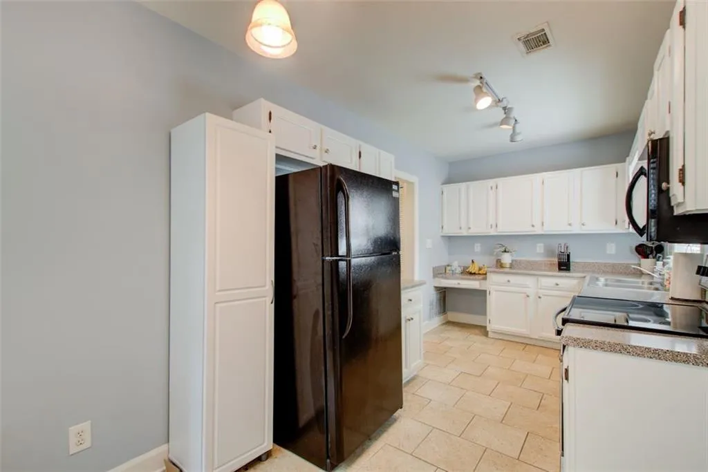 cabinets, light stone counters, rail lighting, and light tile floors