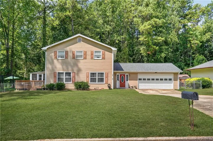 Two-story exterior with neutral siding, front-facing two-car garage, and an inviting red entry door