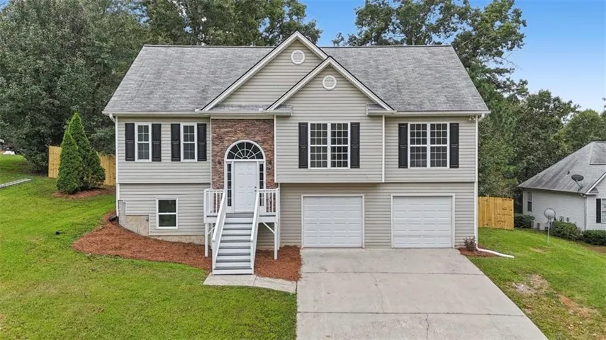 Split-level residence featuring a brick facade accent, arched entryway, two-car garage, and a concrete driveway