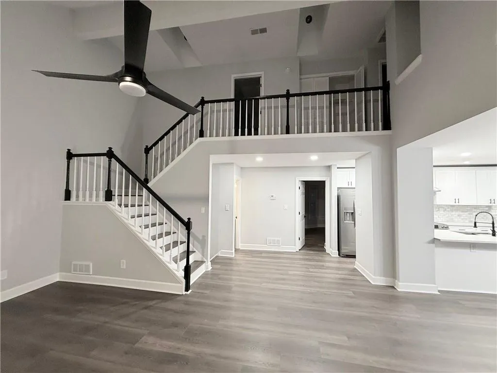 Unfurnished living room with dark wood finished floors, a ceiling fan, recessed lighting, and a high ceiling