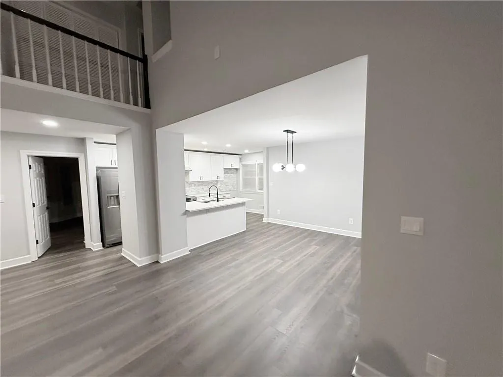 Unfurnished living room featuring dark wood-style floors and hanging lights