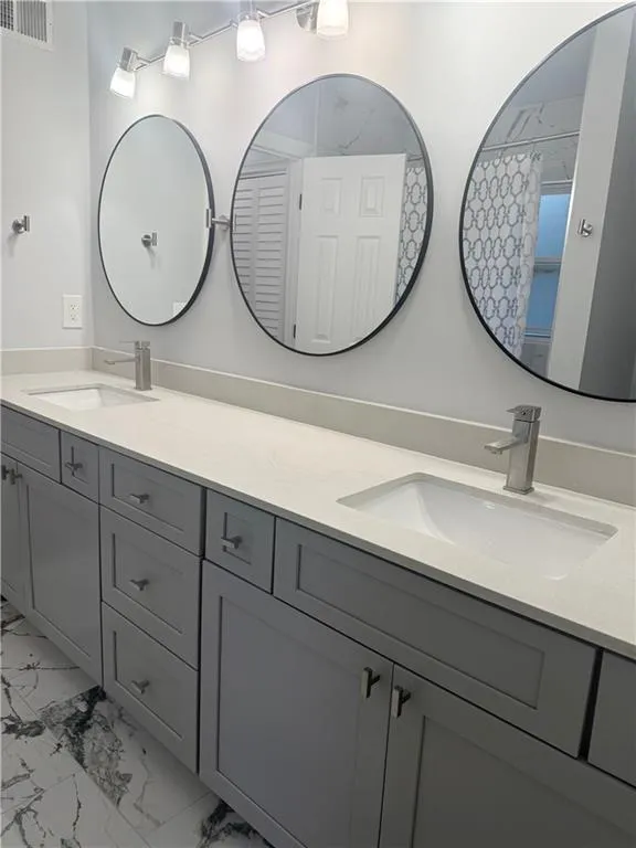 Bathroom featuring double vanity and light marble finish floors