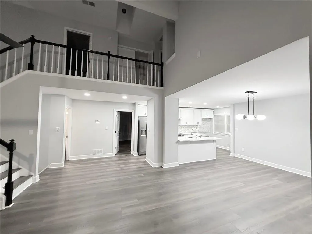 Unfurnished living room with recessed lighting, dark wood-style floors, and a high ceiling