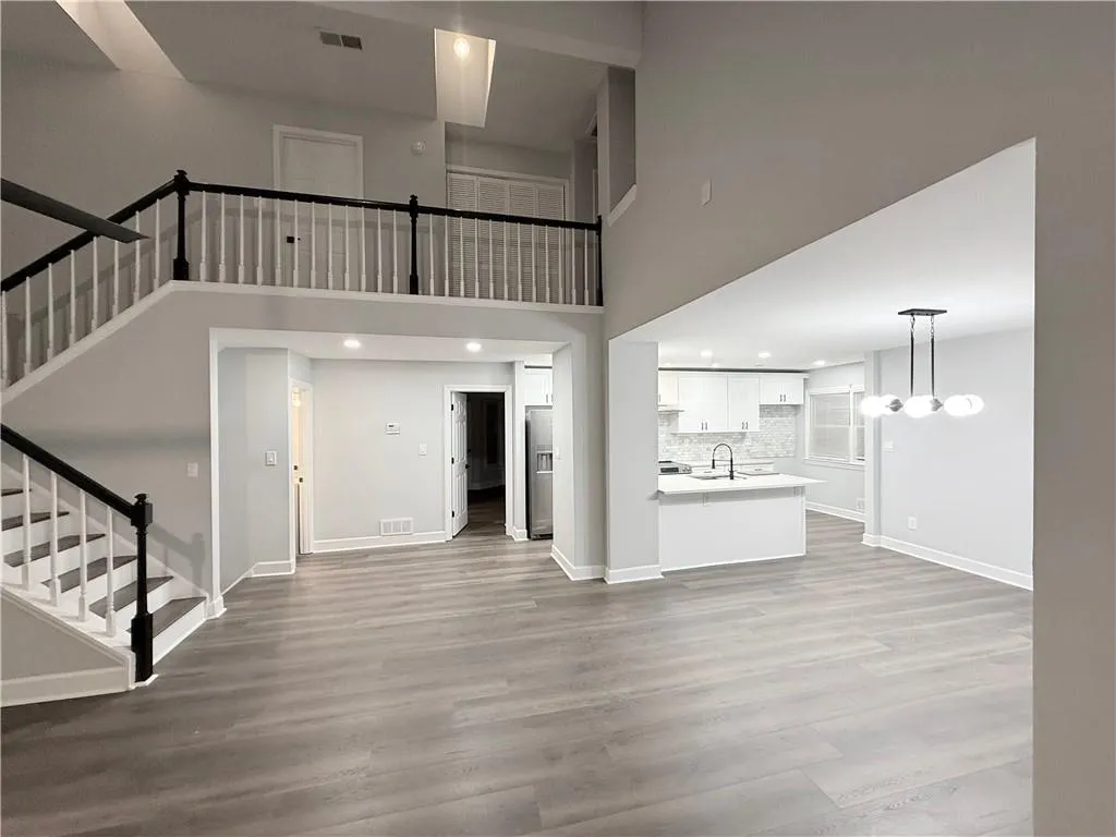 Unfurnished living room featuring light wood finished floors, recessed lighting, and a high ceiling