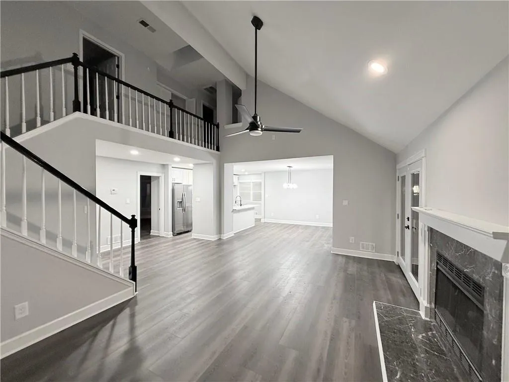 Unfurnished living room featuring a premium fireplace, ceiling fan, recessed lighting, dark wood-style flooring, and lofted ceiling