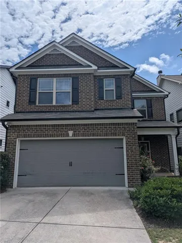 Two-story brick exterior featuring a two-car garage with decorative hardware