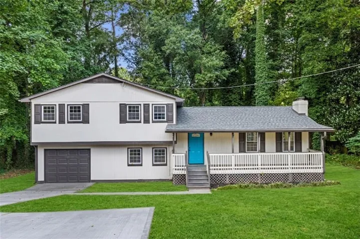 White siding exterior with dark shutters, covered front porch, vibrant blue entry door, and an attached garage