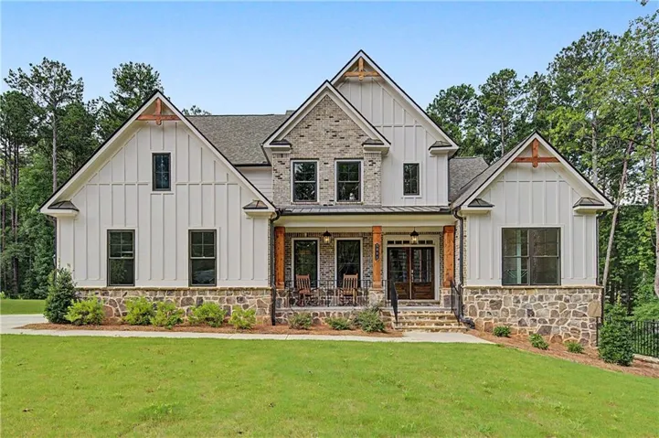 Crafted residence featuring a stone foundation, board and batten siding, and a covered front porch with substantial wood columns
