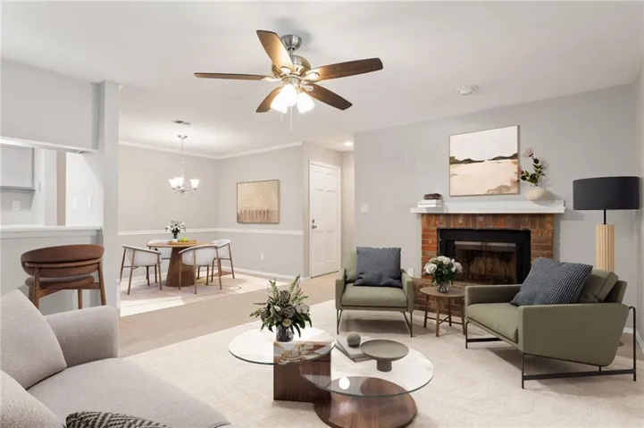 Living area featuring a brick fireplace with a white mantel, ceiling fan, and carpeted flooring