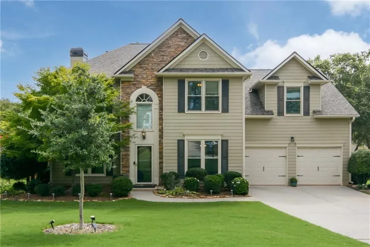 Two-story residence featuring a stone and siding exterior, arched window over the entry, and a two-car garage