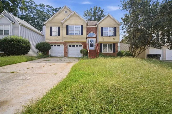 Exterior featuring a two-car garage, brick accents, and a front entry with an arched transom window