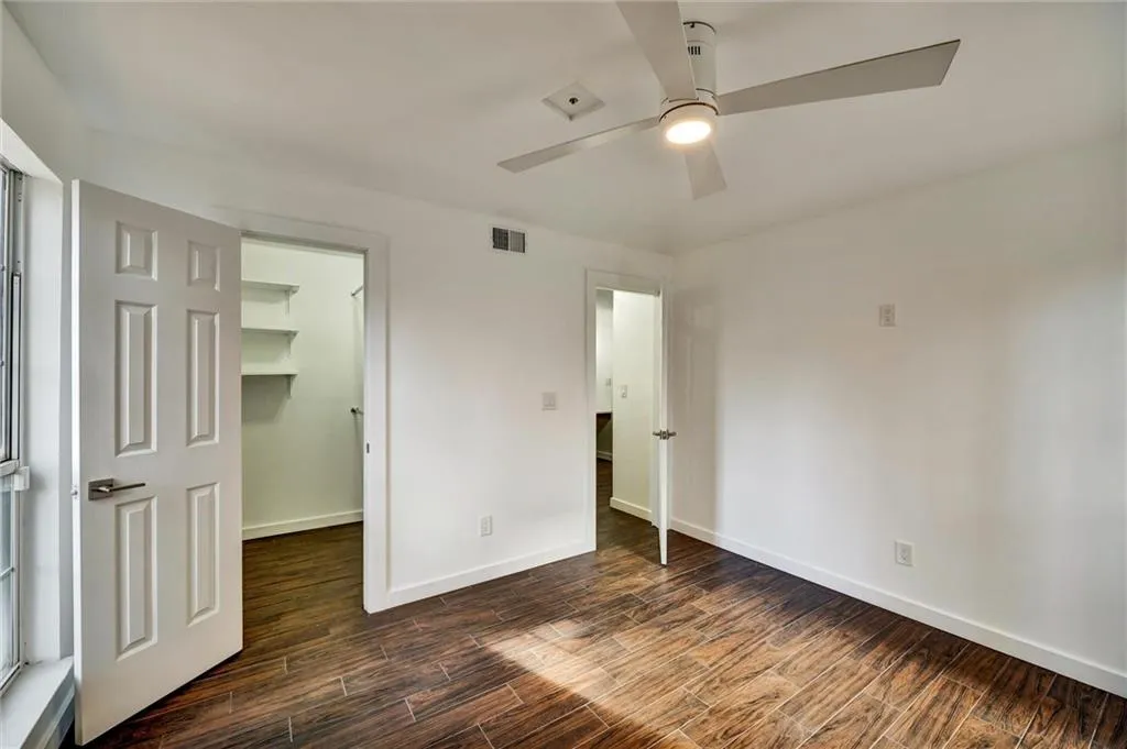 Unfurnished bedroom featuring a spacious closet, wood tiled floors, and ceiling fan