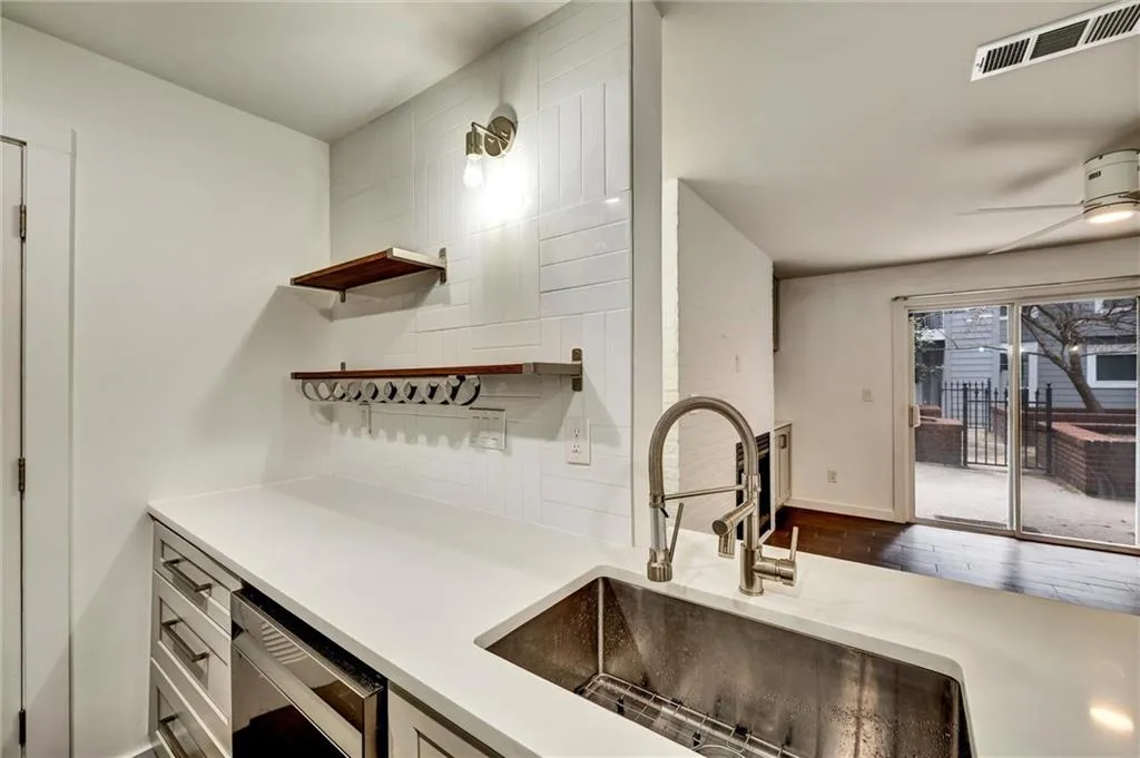 Kitchen featuring open shelves, a ceiling fan, dark wood-style flooring, decorative backsplash, and light stone counters