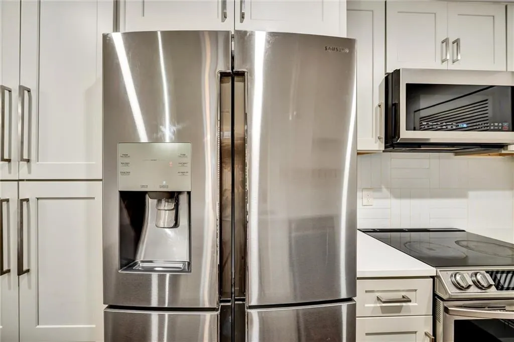 Kitchen featuring appliances with stainless steel finishes, white cabinets, and light stone countertops