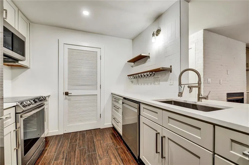 Kitchen featuring open shelves, appliances with stainless steel finishes, wood finish floors, light stone counters, and white cabinets