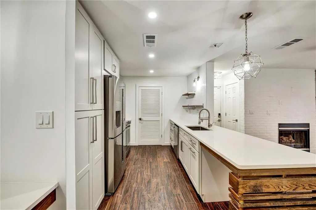 Kitchen featuring a peninsula, white cabinets, recessed lighting, stainless steel appliances, and dark wood finished floors