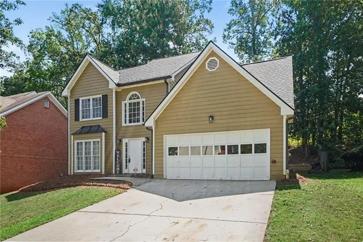 Two-story residence featuring a two-car garage, pitched roofline, and dormer windows