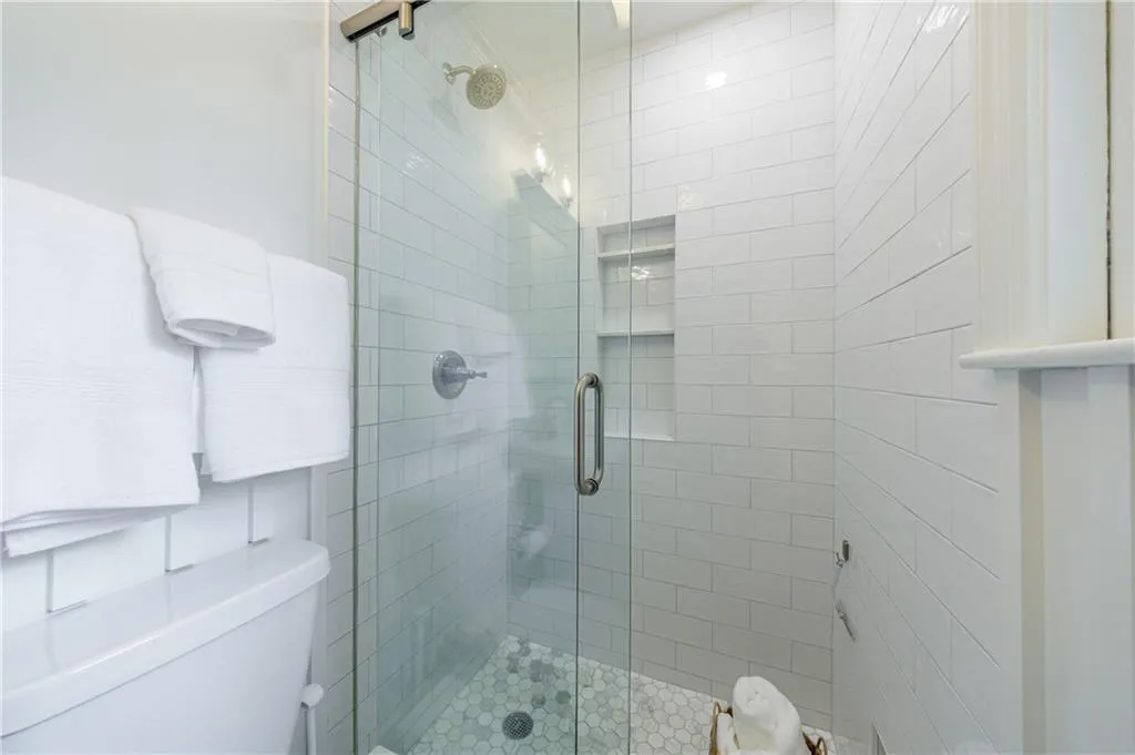 Full bath featuring a shower stall and toilet
