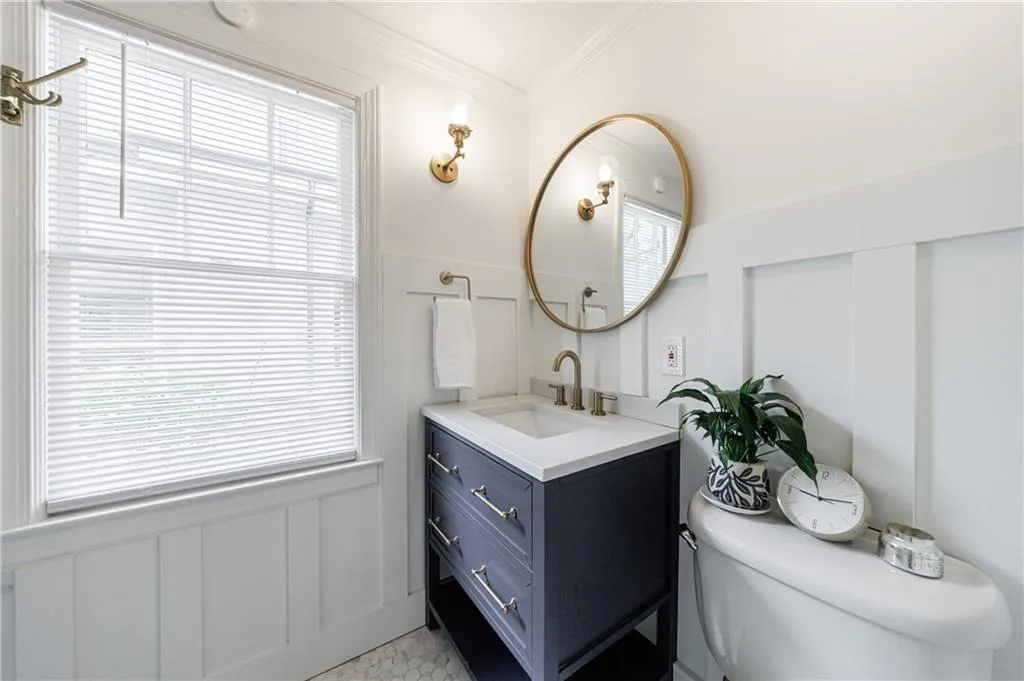 Bathroom featuring toilet, ornamental molding, vanity, a decorative wall, and healthy amount of natural light