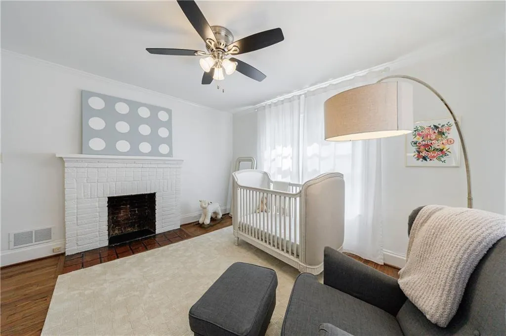 Bedroom with crown molding, a brick fireplace, ceiling fan, baseboards, and wood finished floors