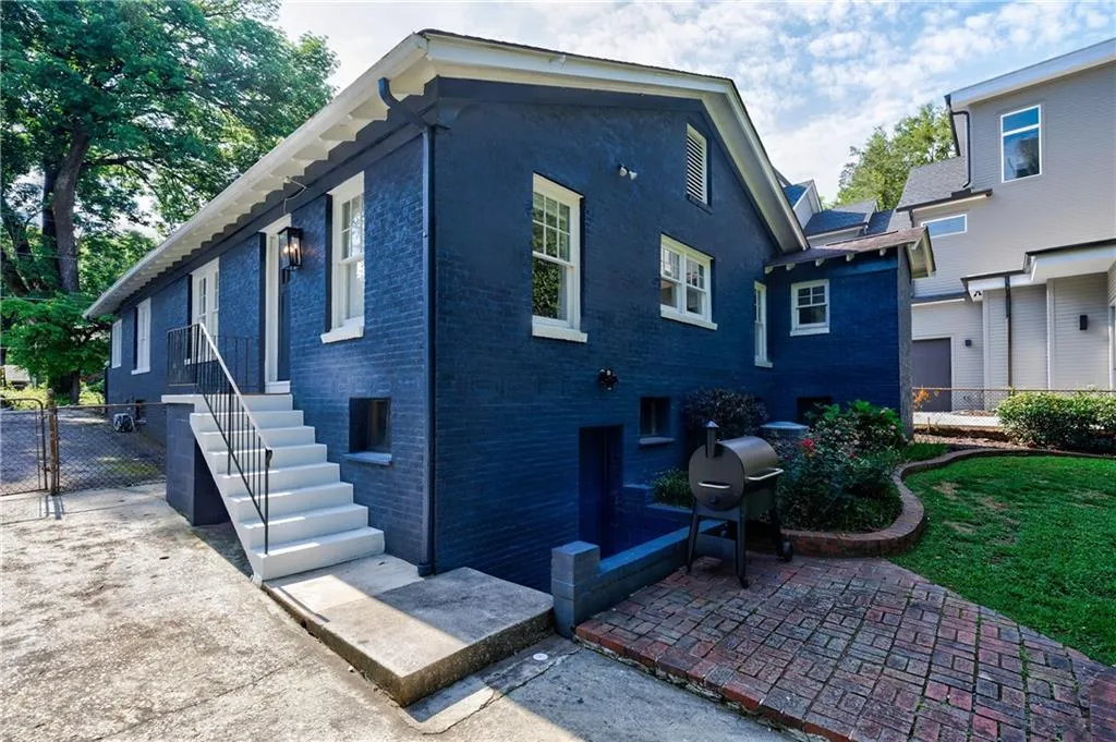 View of property exterior featuring brick siding, a patio, and a gate