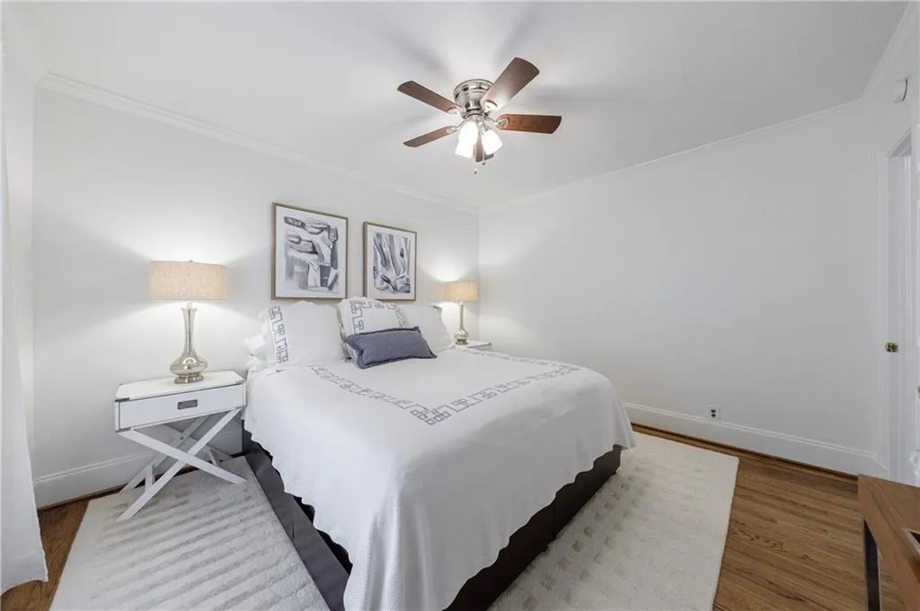 Bedroom featuring wood finished floors, crown molding, baseboards, and ceiling fan